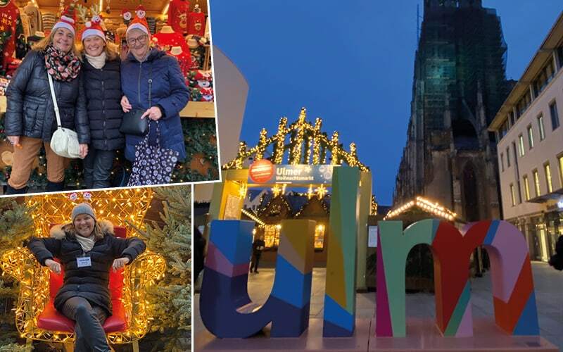 Voyageuses en bonnets de Noël, trône illuminé et lettres colorées Ulm devant le marché de Noël