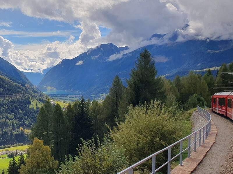 Train rouge de la Bernina surplombant le Valposchiavo et son lac entre des montagnes nuageuses