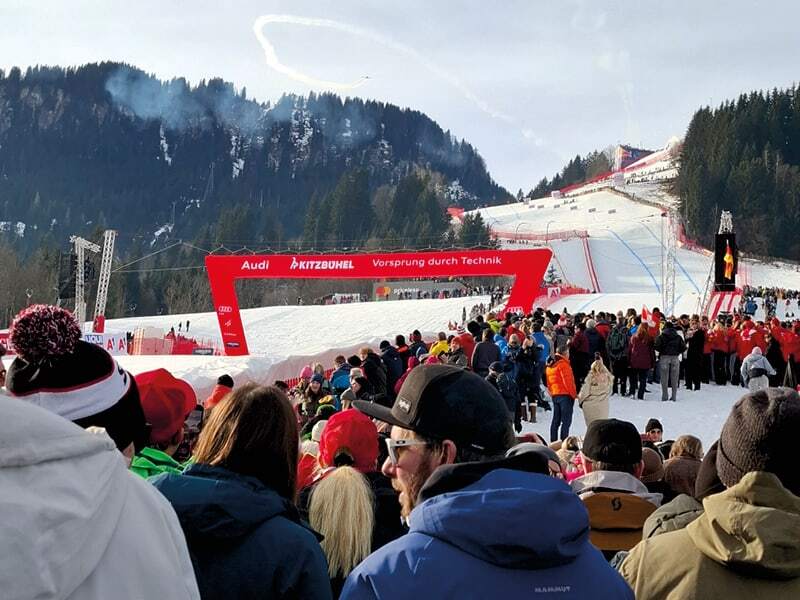 Foule massée devant l’arche d’arrivée rouge de Kitzbühel, au pied de la piste enneigée