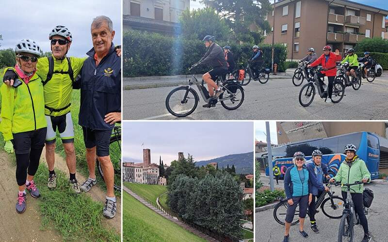 Groupe partant à vélo électrique, cyclistes casqués souriants devant le car et ville aux tours médiévales