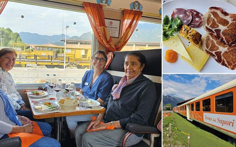 Voyageuses attablées dans le train des saveurs, assiette de fromages et charcuterie et wagon orange