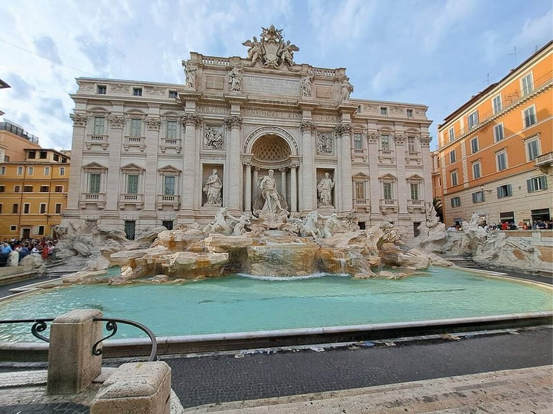 Fontaine de Trevi et ses eaux turquoise devant une façade baroque ornée de statues