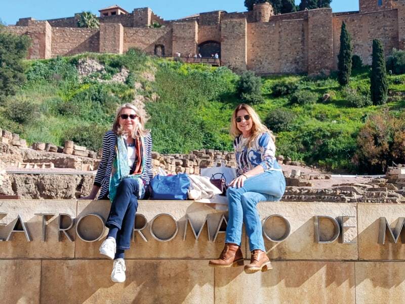 Deux voyageuses assises devant le théâtre romain de Malaga, sous les remparts d’une forteresse
