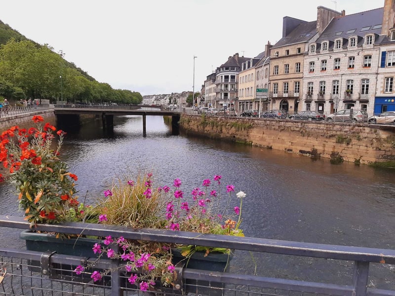 Fluss mit Brücke, Blumen und historischen Häusern entlang des Ufers in Quimper, Bretagne.