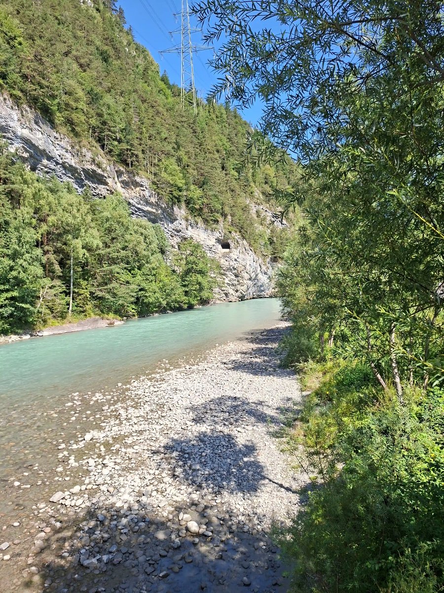 Flusslandschaft in einem bewaldeten Tal mit felsigem Ufer.