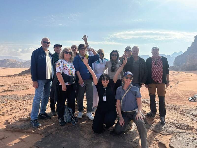 Groupe de voyageurs souriants sur un rocher dans le désert du Wadi Rum