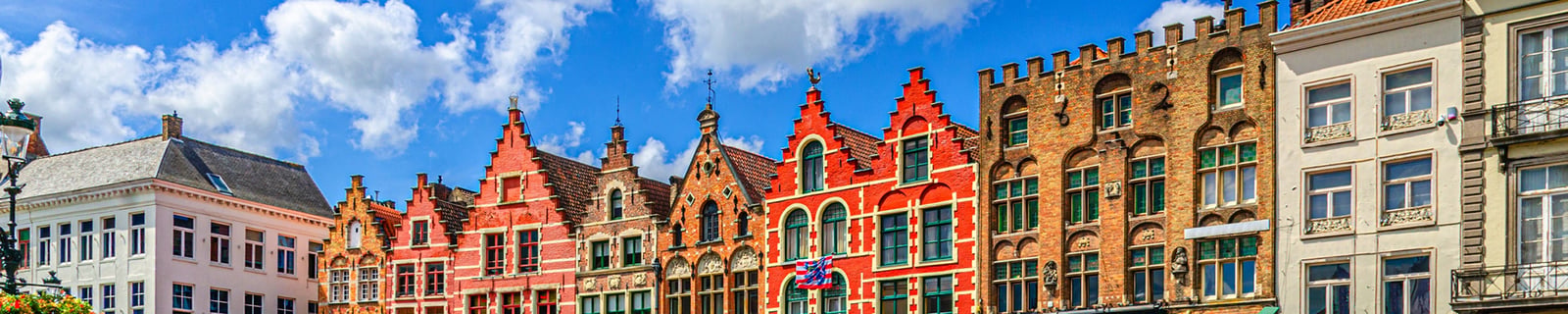 Façades colorées à pignons à gradins de Bruges sous un ciel bleu