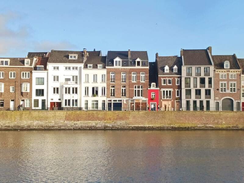 Maisons colorées alignées le long d’un quai de la Meuse à Maastricht