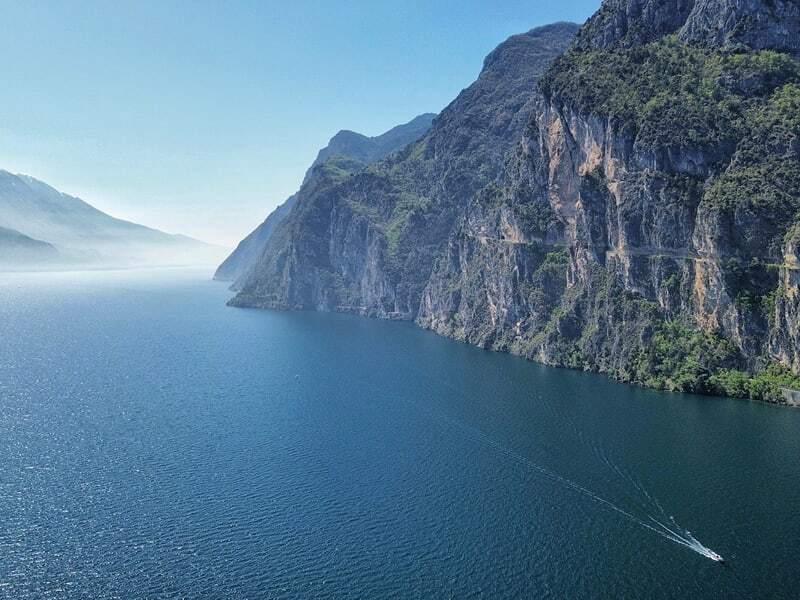 Falaises abruptes plongeant dans le lac de Garde, avec un bateau et son sillage