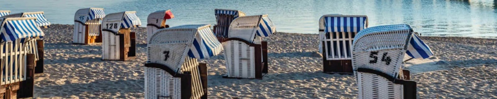 Corbeilles de plage rayées de bleu et blanc sur le sable au bord de la mer
