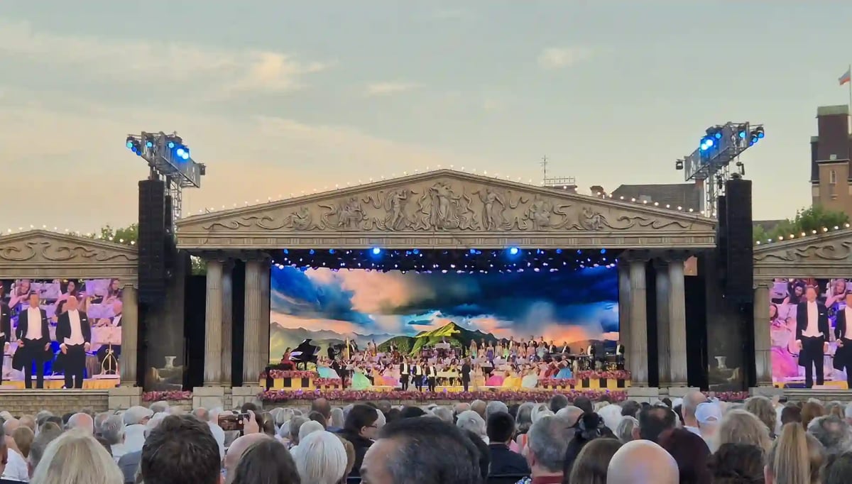 Grosses Open-Air-Konzert mit Orchester auf einer festlich beleuchteten Bühne vor zahlreichem Publikum.