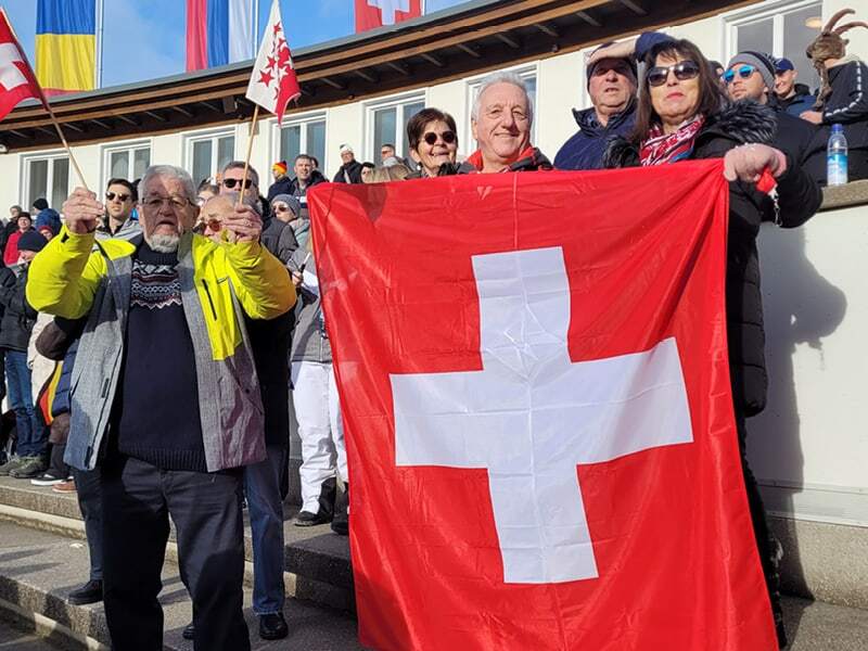 Voyageurs tenant un grand drapeau suisse dans la tribune du saut à ski de Garmisch-Partenkirchen