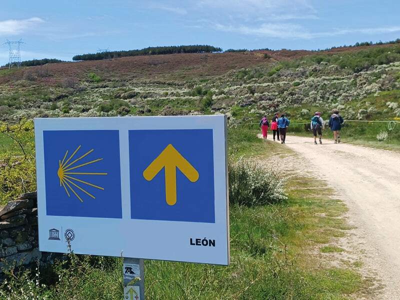 Coquille et flèche jaunes du chemin de Saint-Jacques en province de León, randonneurs sur un sentier