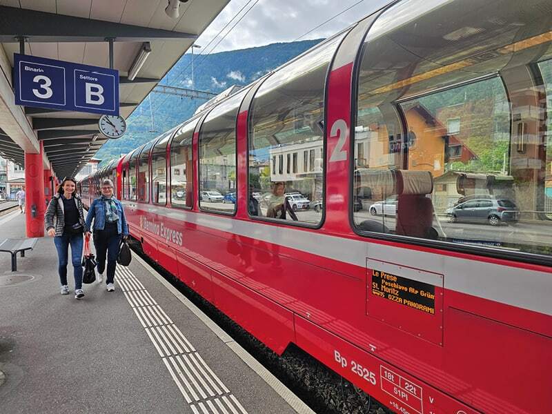 Deux voyageuses sur le quai à côté des voitures panoramiques rouges du Bernina Express