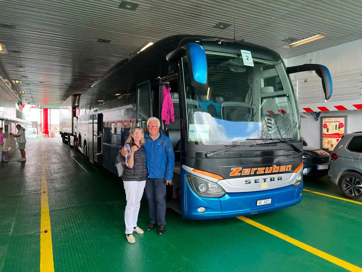 Gäste vor dem car-tours.ch Reisebus auf einer Fähre.