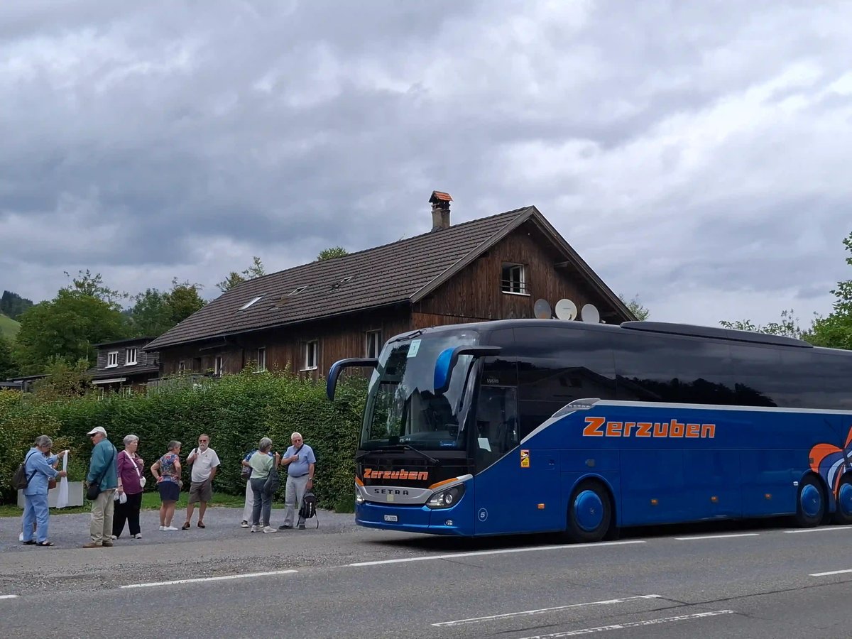 Car de tourisme bleu stationné devant un bâtiment traditionnel en bois