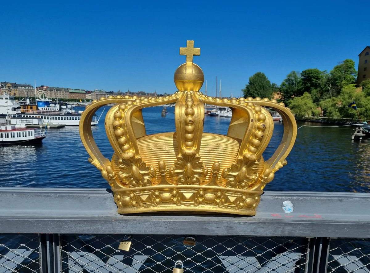 Goldene Krone auf einer Brücke mit Blick auf Boote und Häuser in Stockholm