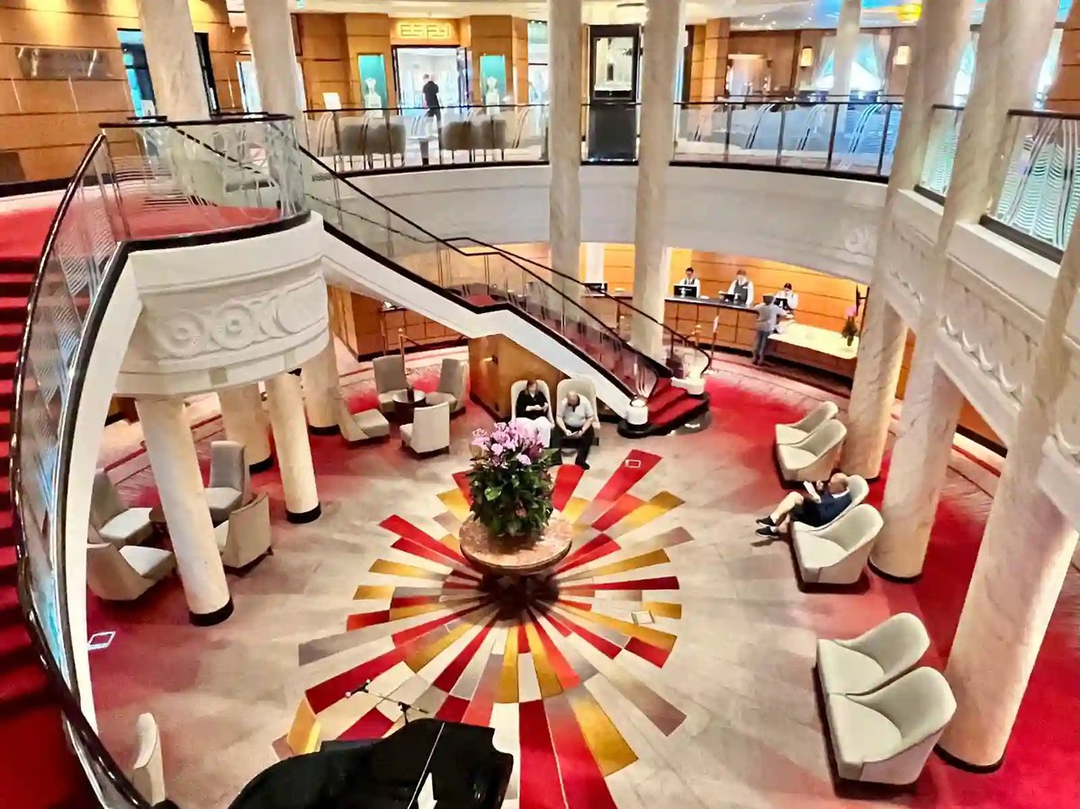 Mehrstöckige Grand Lobby der Queen Mary 2 mit Treppen, Sitzgruppen und Flügel