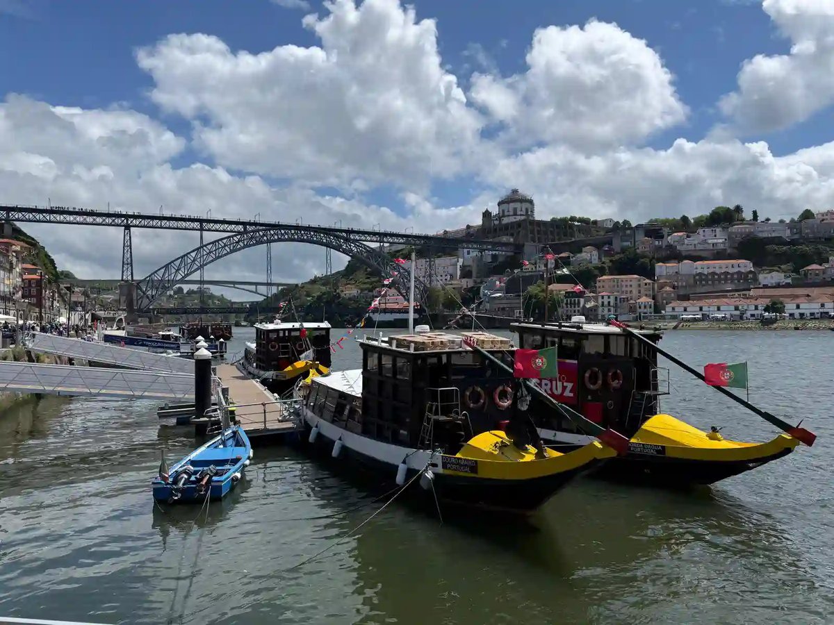 Traditionelle Portweinboote auf dem Douro in Porto mit der Dom-Luís-I-Brücke im Hintergrund.