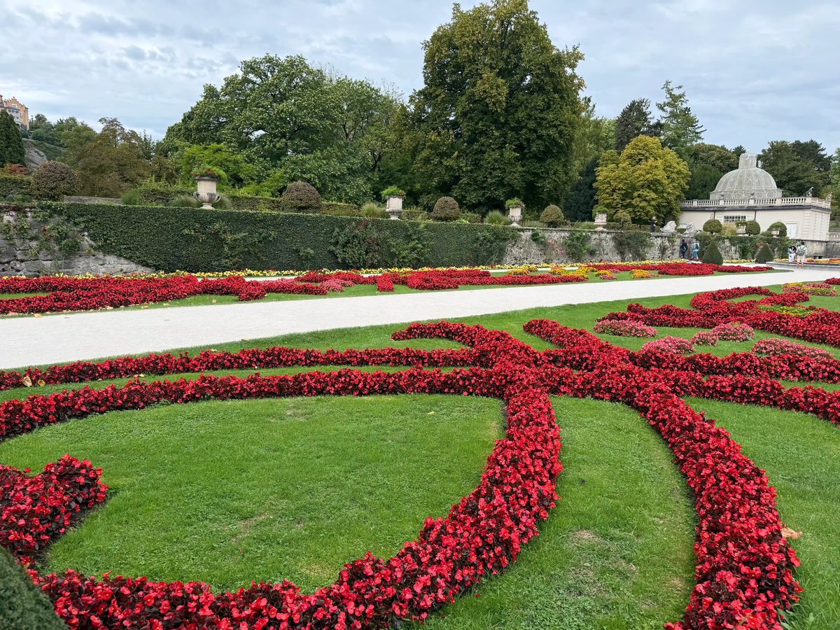 Parterres de fleurs rouges et blanches entourés de pelouses verdoyantes dans les jardins de Mirabell