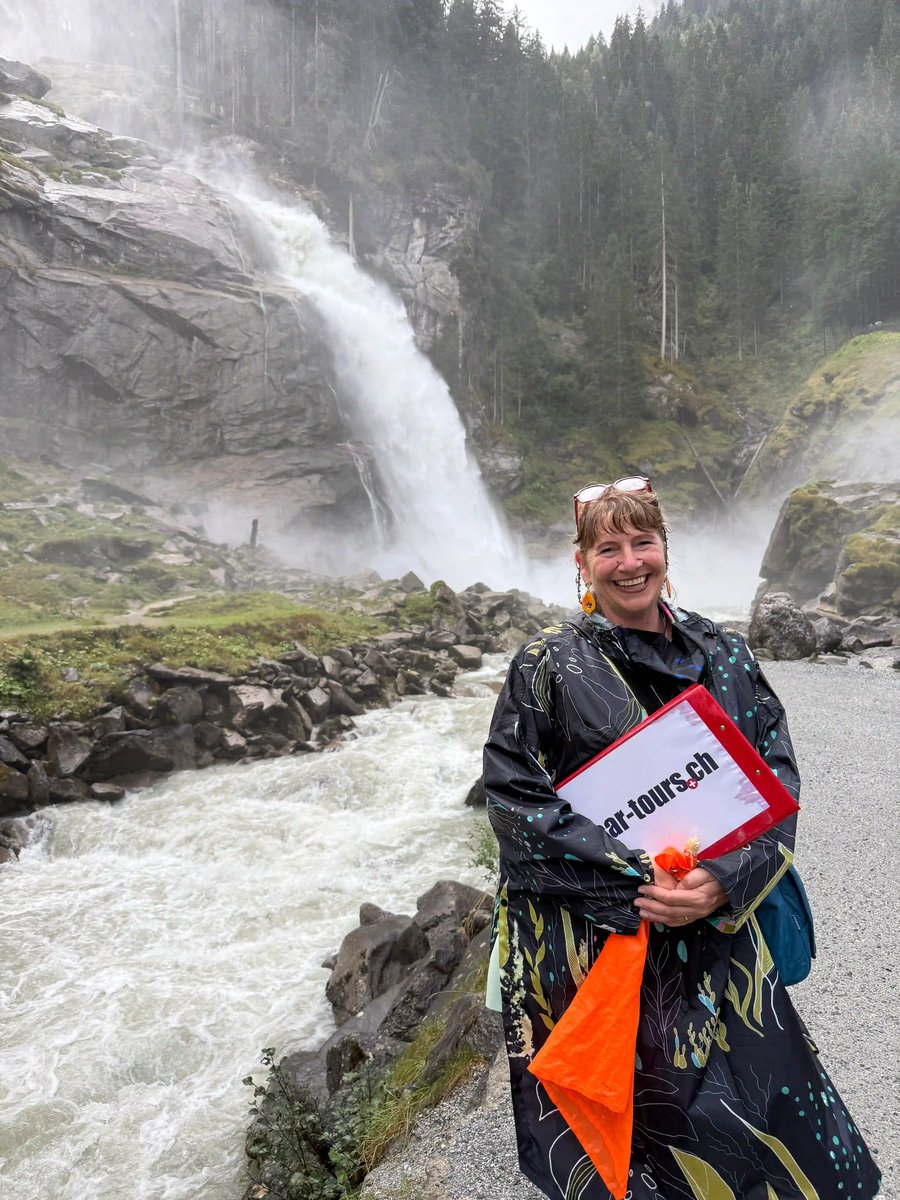 Une femme pose devant une puissante cascade, entourée de rochers et de végétation