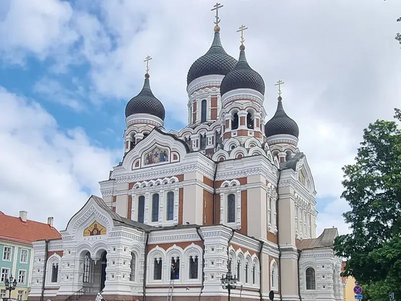 Orthodoxe Kirche mit Kuppeln und Kreuzen vor wolkigem Himmel
