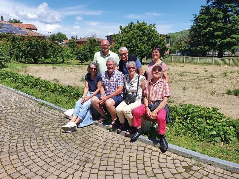 Gruppe von Personen sitzt auf einer Bank in sonniger Umgebung mit Garten