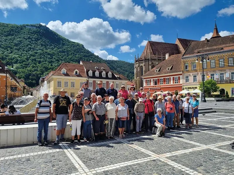 Reisegruppe auf Platz in historischer Stadt mit bunten Gebäuden und Bergen