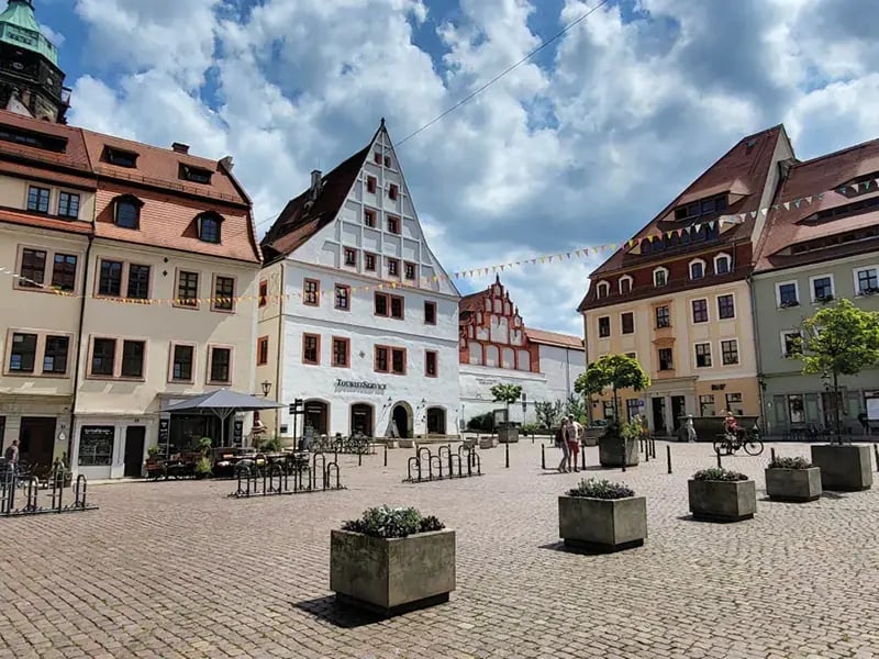 Historischer Marktplatz mit farbigen Giebelhäusern, Pflasterstein und wenigen Menschen