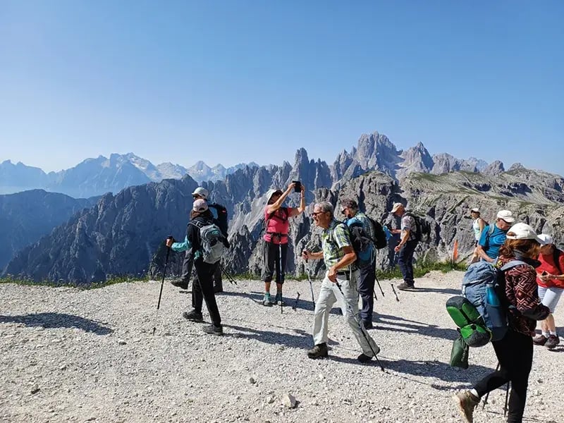 Wandergruppe auf Bergplateau mit Blick auf hohe Felsberge und blauem Himmel