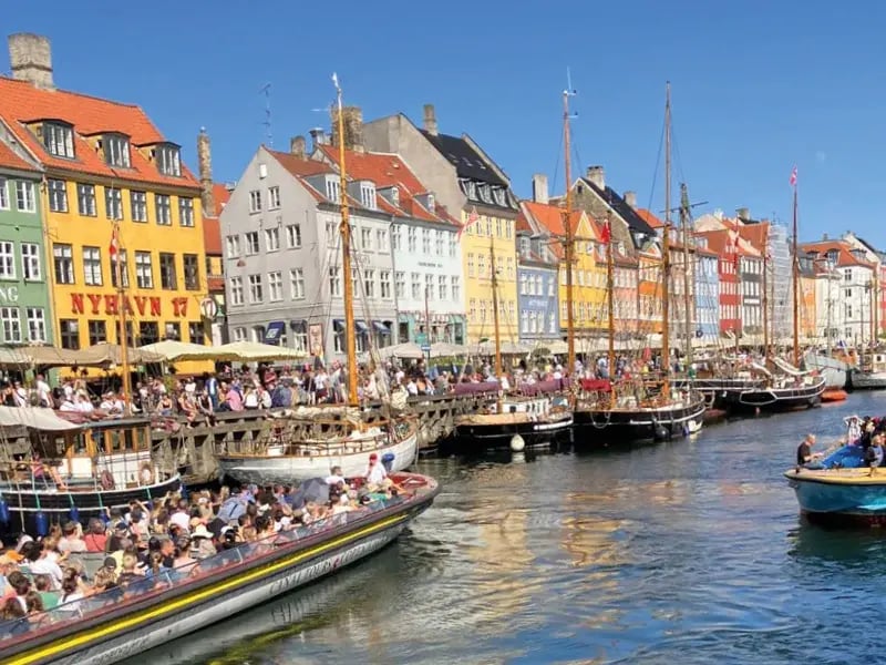 Hafen in Kopenhagen mit bunten Häusern, Booten und vielen Menschen am Ufer