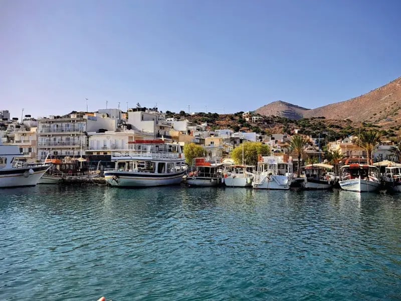 Hafen mit Booten, weissen Gebäuden und Hügeln im Hintergrund
