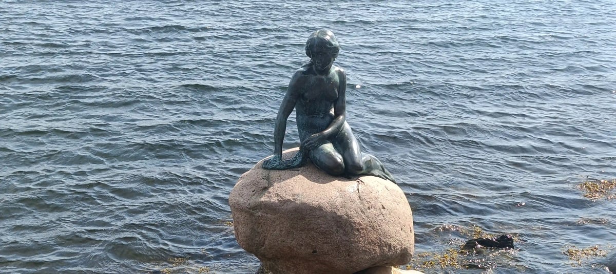 Bronzestatue der Kleinen Meerjungfrau auf einem Felsen am Wasser