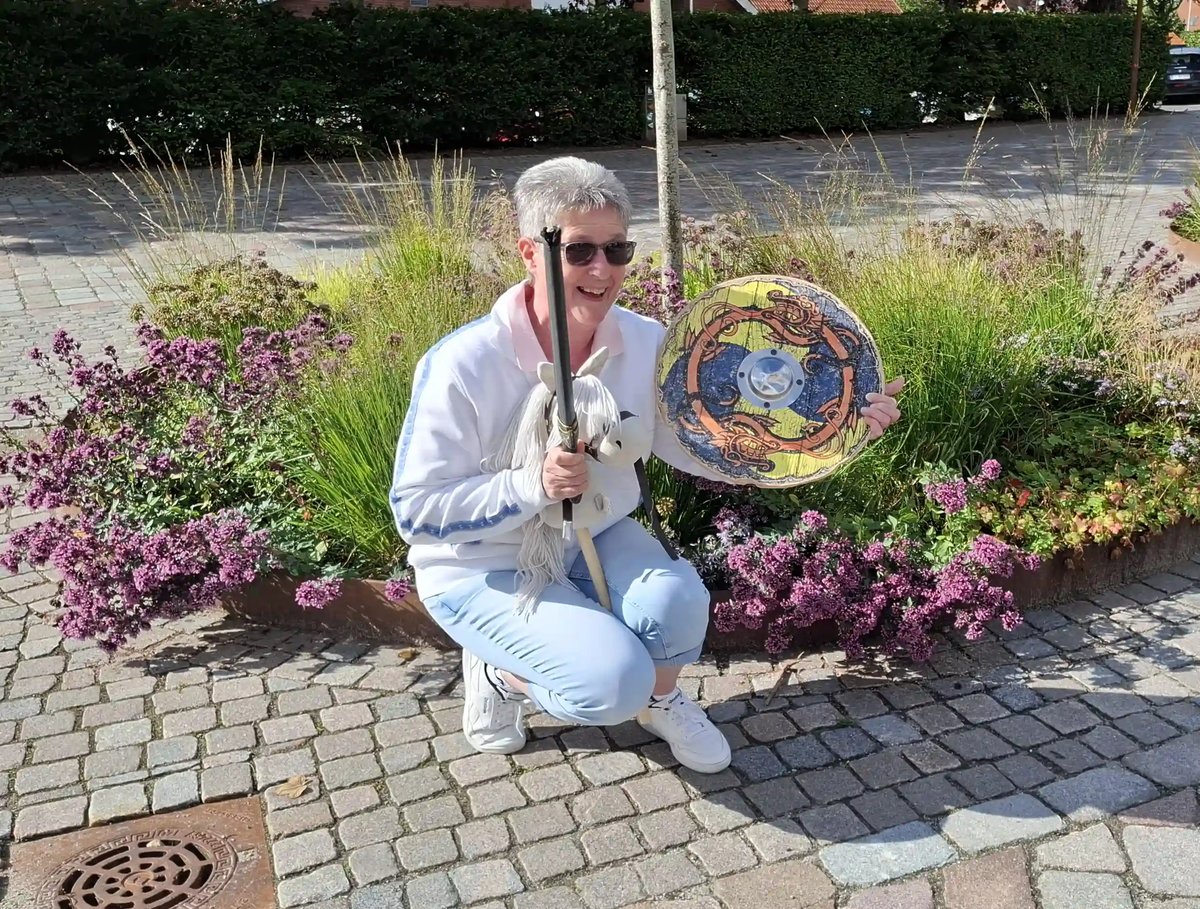 Lachende Reiseleiterin mit Wikingerhelm, Schwert und Schild in Dänemark