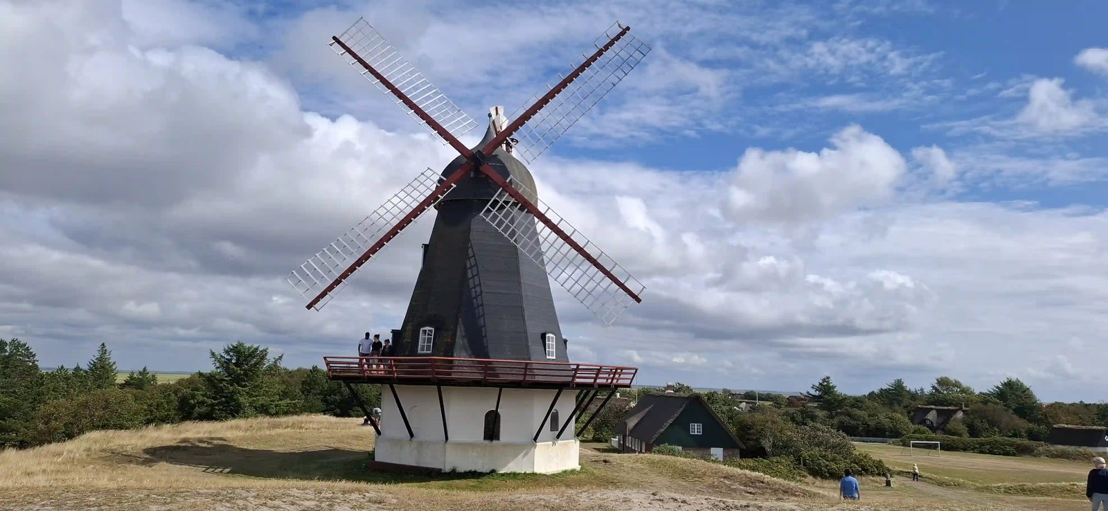 Historische dänische Windmühle mit vier Flügeln unter blau-weissem Wolkenhimmel