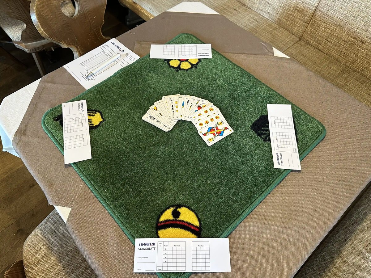 Jassteppich mit ausgelegten Spielkarten und Zählblättern, vorbereitet für ein Jassturnier.
