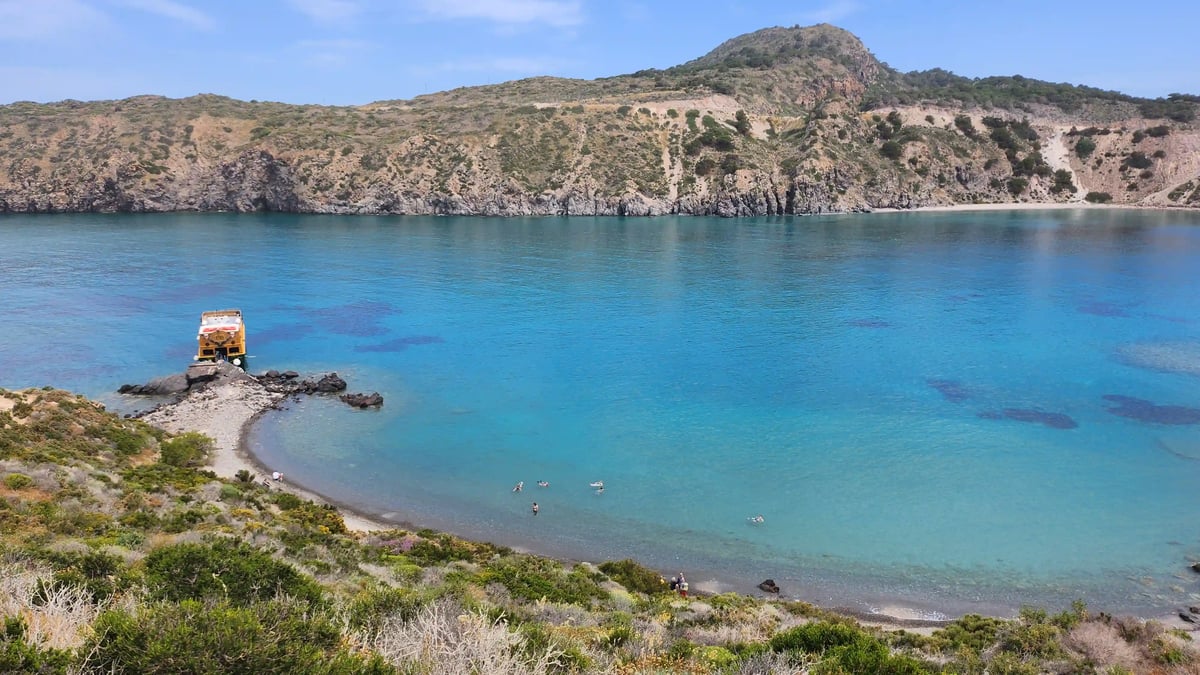 Türkisblaue Bucht mit felsiger Küstenlandschaft und Segelbooten bei Symi.