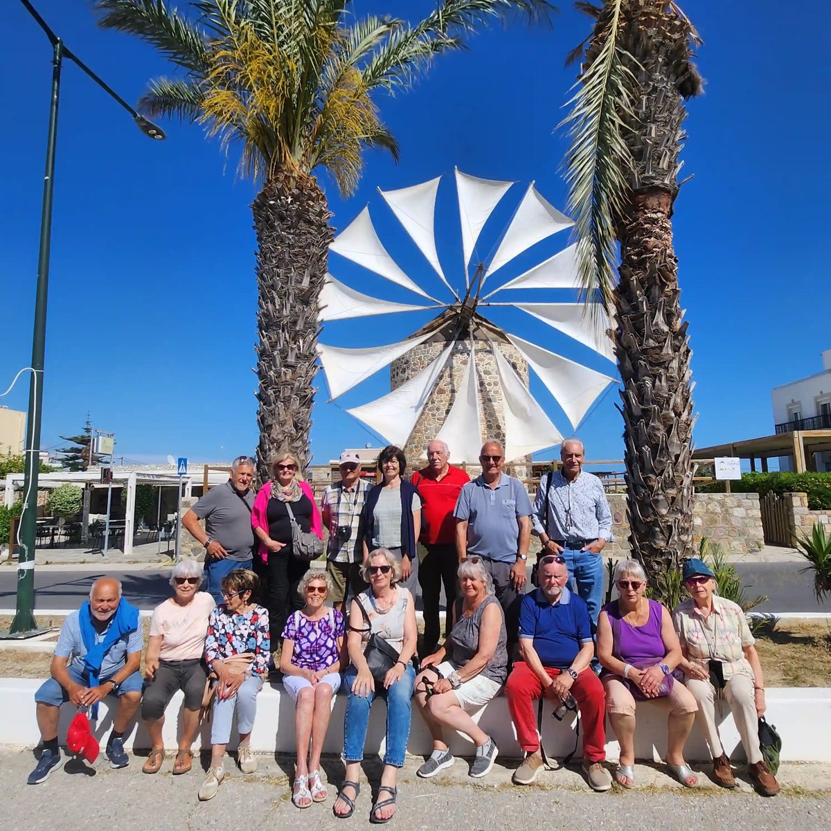 Reisegruppe vor einer traditionellen Windmühle zwischen Palmen auf Kos