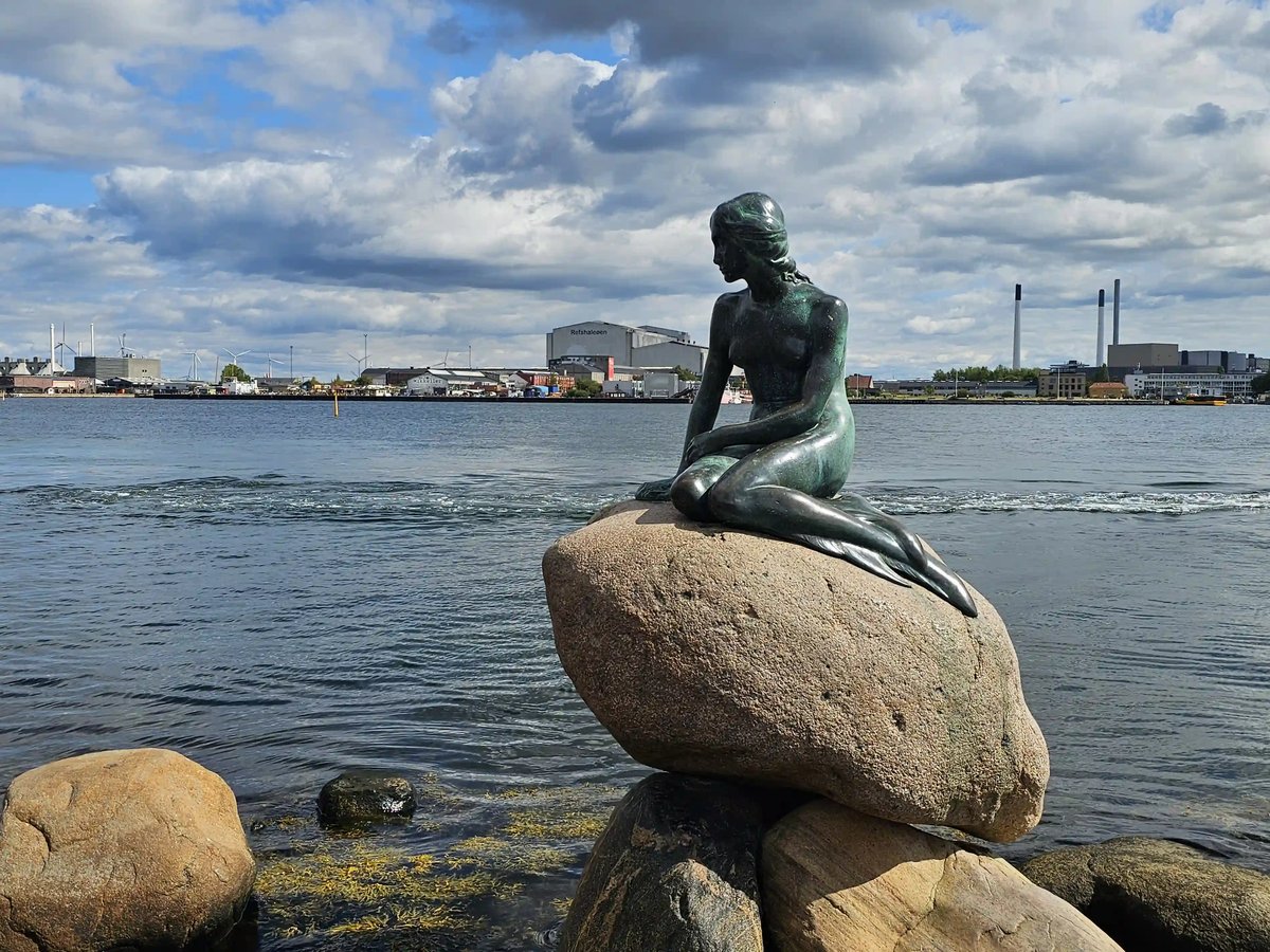 Bronzestatue der Kleinen Meerjungfrau auf einem Felsen am Wasser in Kopenhagen