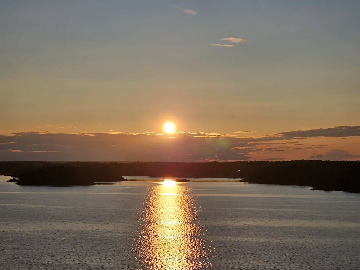 Goldener Sonnenuntergang über dem Meer mit dunklen Inseln und leuchtender Spiegelung auf dem Wasser
