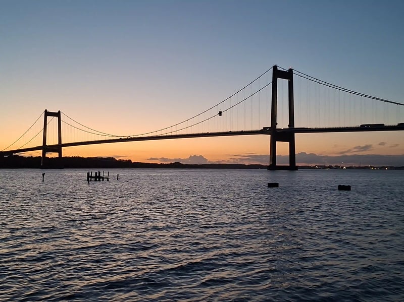 Grosse Hängebrücke über dem Meer im warmen Licht des Sonnenuntergangs