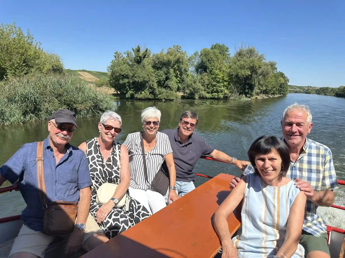 Fröhliche Reisegruppe bei einer sonnigen Schifffahrt auf dem Main.