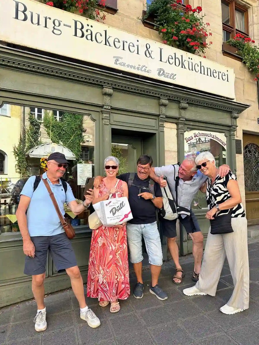 Fünf gut gelaunte Reisegäste vor einer traditionellen Burg-Bäckerei und Lebküchnerei in Nürnberg.