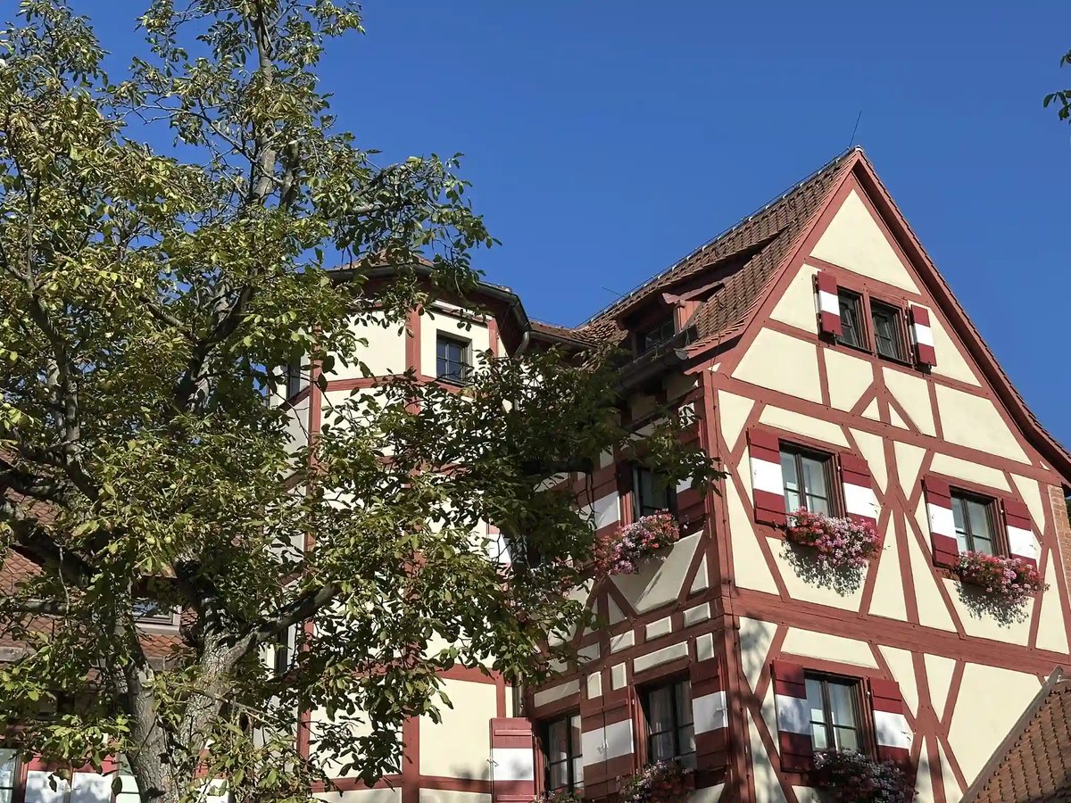 Historisches Fachwerkhaus mit roten Fensterläden und Blumenschmuck in Nürnberg.