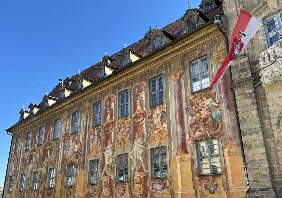 Historisches Gebäude mit kunstvoll bemalter Fassade unter blauem Himmel in Bamberg.