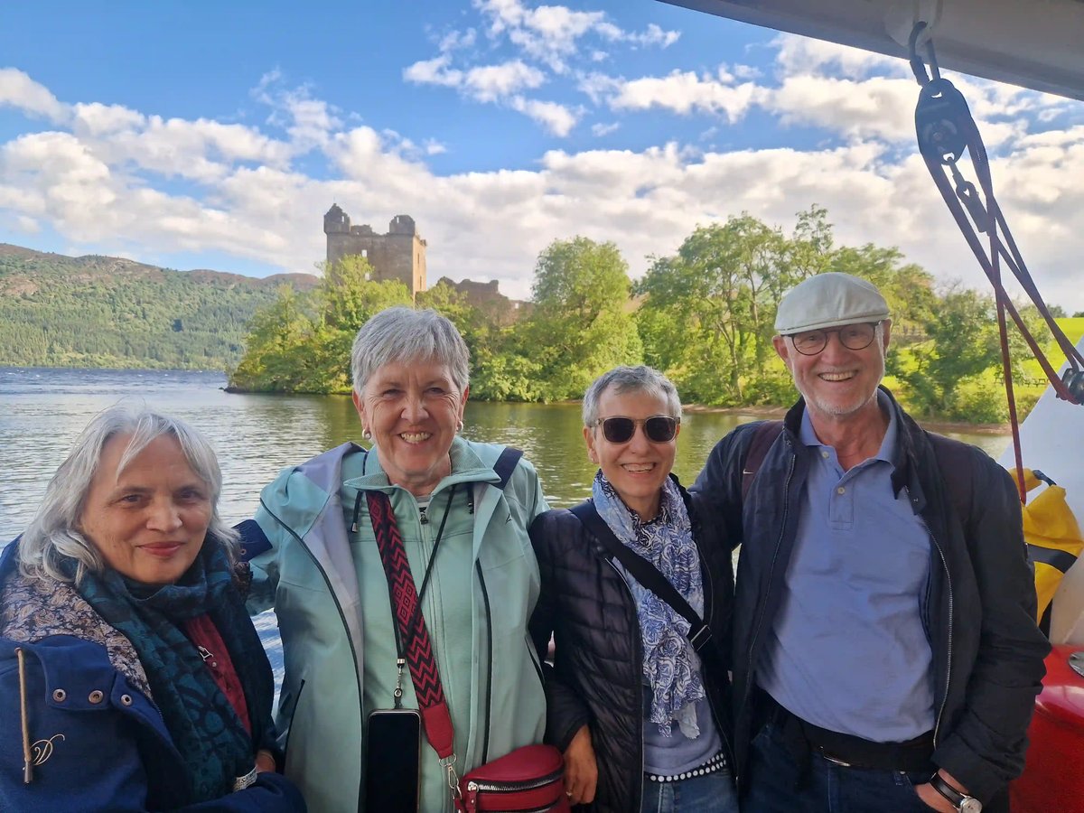 Reisegäste bei einer Bootsfahrt auf Loch Ness mit Urquhart Castle im Hintergrund.