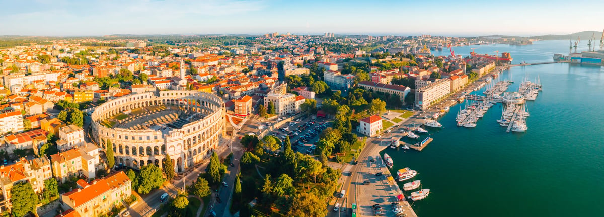 Luftaufnahme des Amphitheaters in Pula mit Altstadt, Yachthafen und Adriaküste