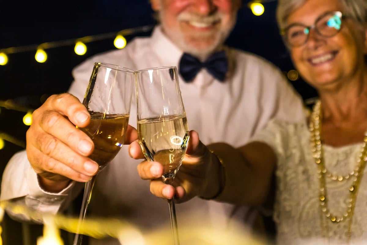Paar stösst mit Sektgläsern auf einer festlich beleuchteten Silvesterfeier an