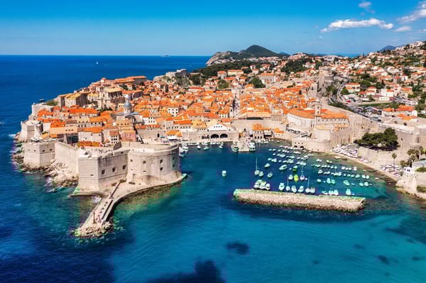 Luftaufnahme der Altstadt von Dubrovnik mit Stadtmauern, orangefarbenen Dächern und Hafen am Adriatischen Meer