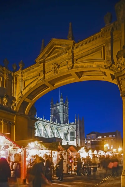 Weihnachtsmarkt in Bath bei Nacht mit festlich beleuchteten Ständen Menschenmenge und historischer Architektur